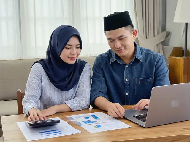 Pasangan menyemak dokumen pembiayaan dengan kalkulator dan komputer riba